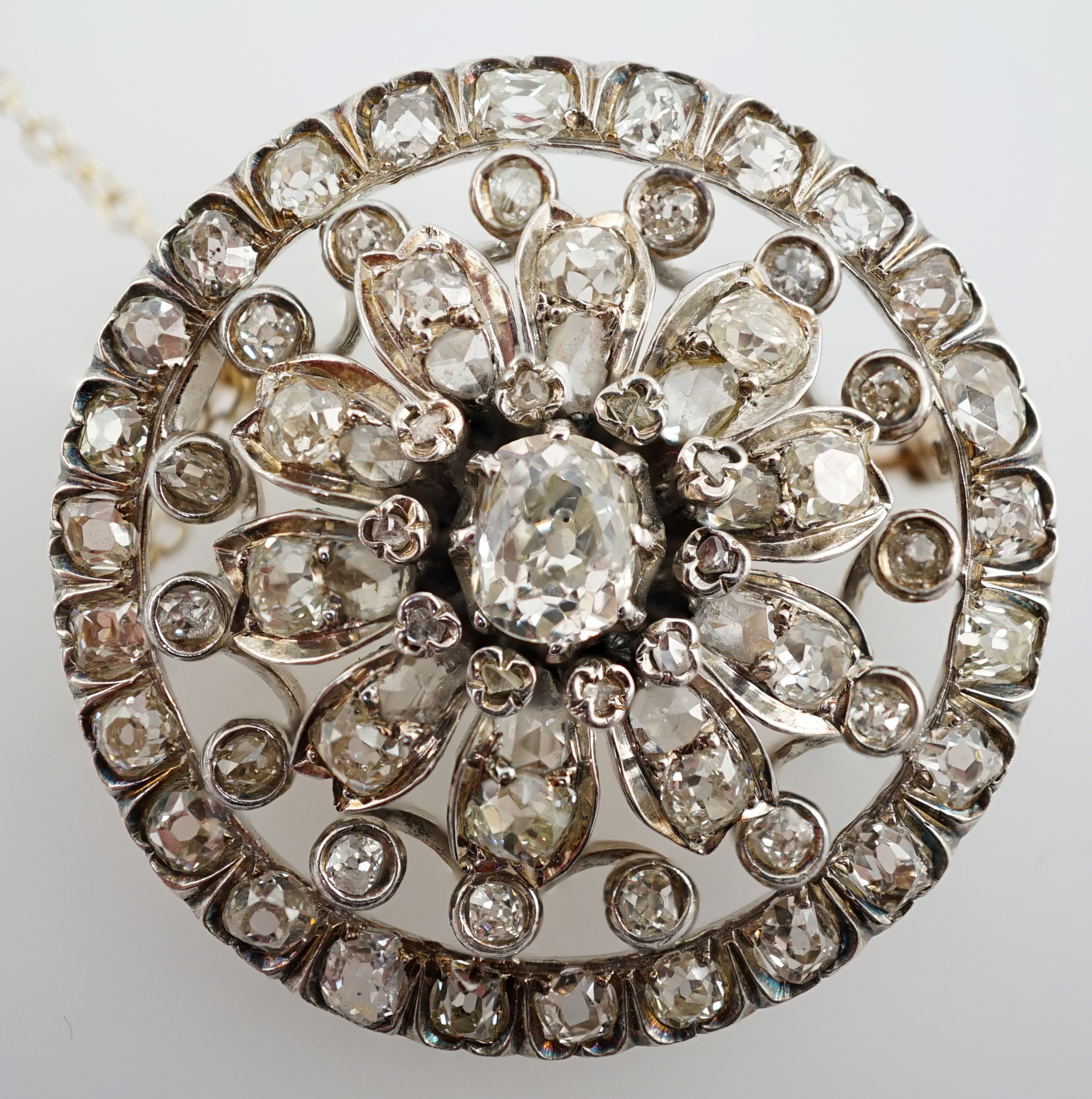 An Edwardian pierced gold and diamond cluster set circular brooch, with central cushion cut stone, diameter 34mm, gross weight 14.4 grams. Condition - fair to good